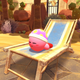 Kirby sleeping on a chaise lounge on a sandy beach.